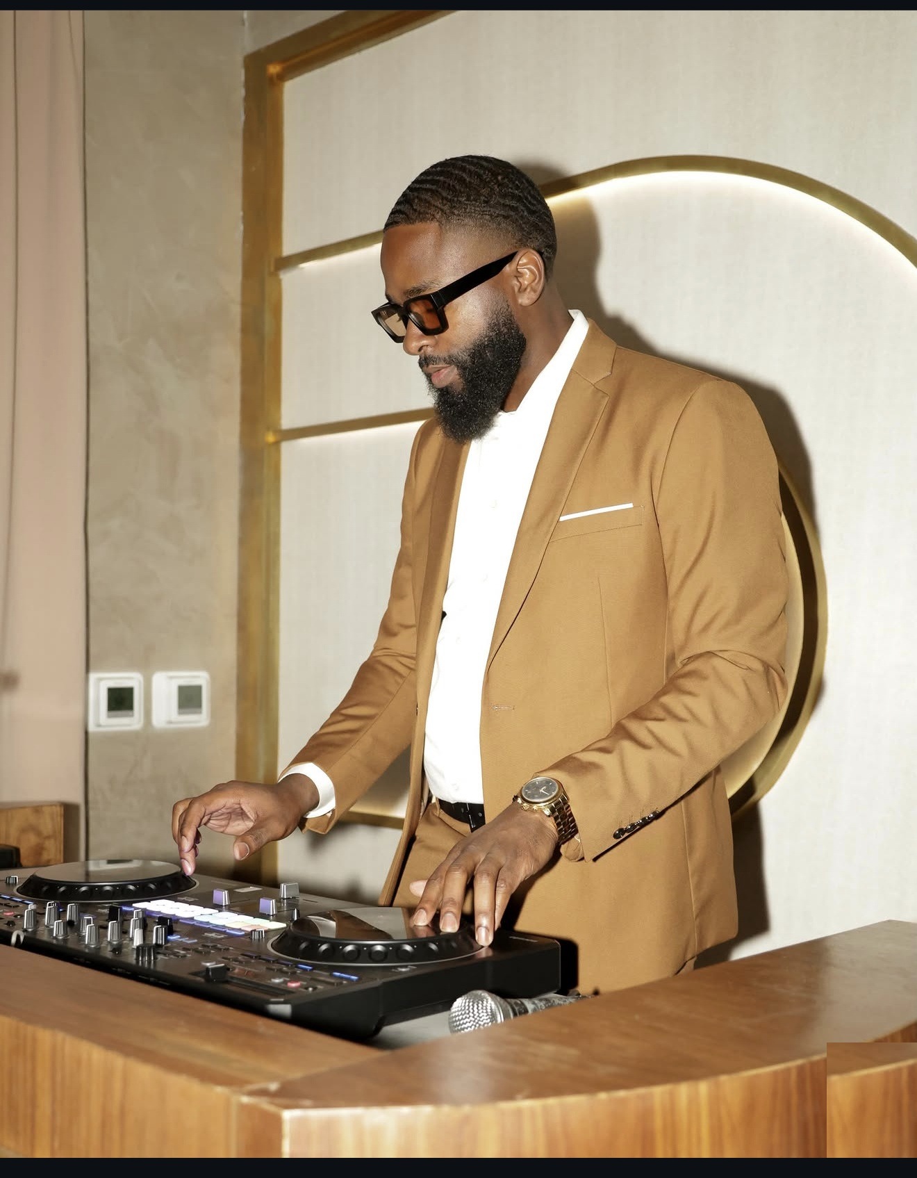 DJ FLYY performing in a tan suit at an event